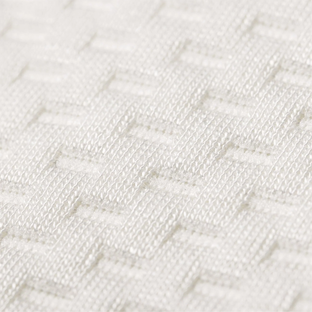 Close-up of a white woven fabric with a textured geometric basketweave pattern.