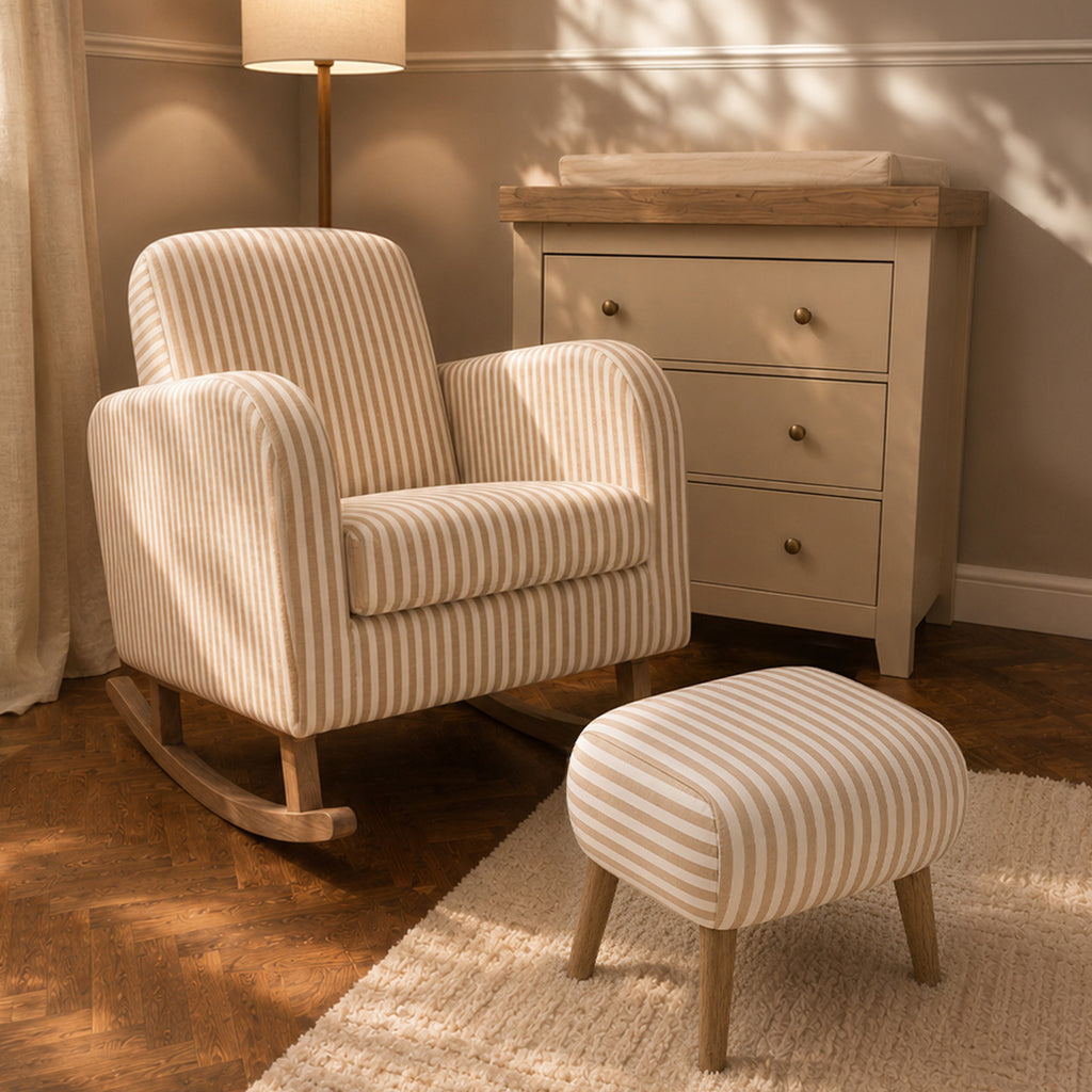 A cream and beige striped rocking armchair with a matching striped ottoman in a softly lit nursery or living room setting, with a wooden dresser, lamp, rug, and wood floor visible.