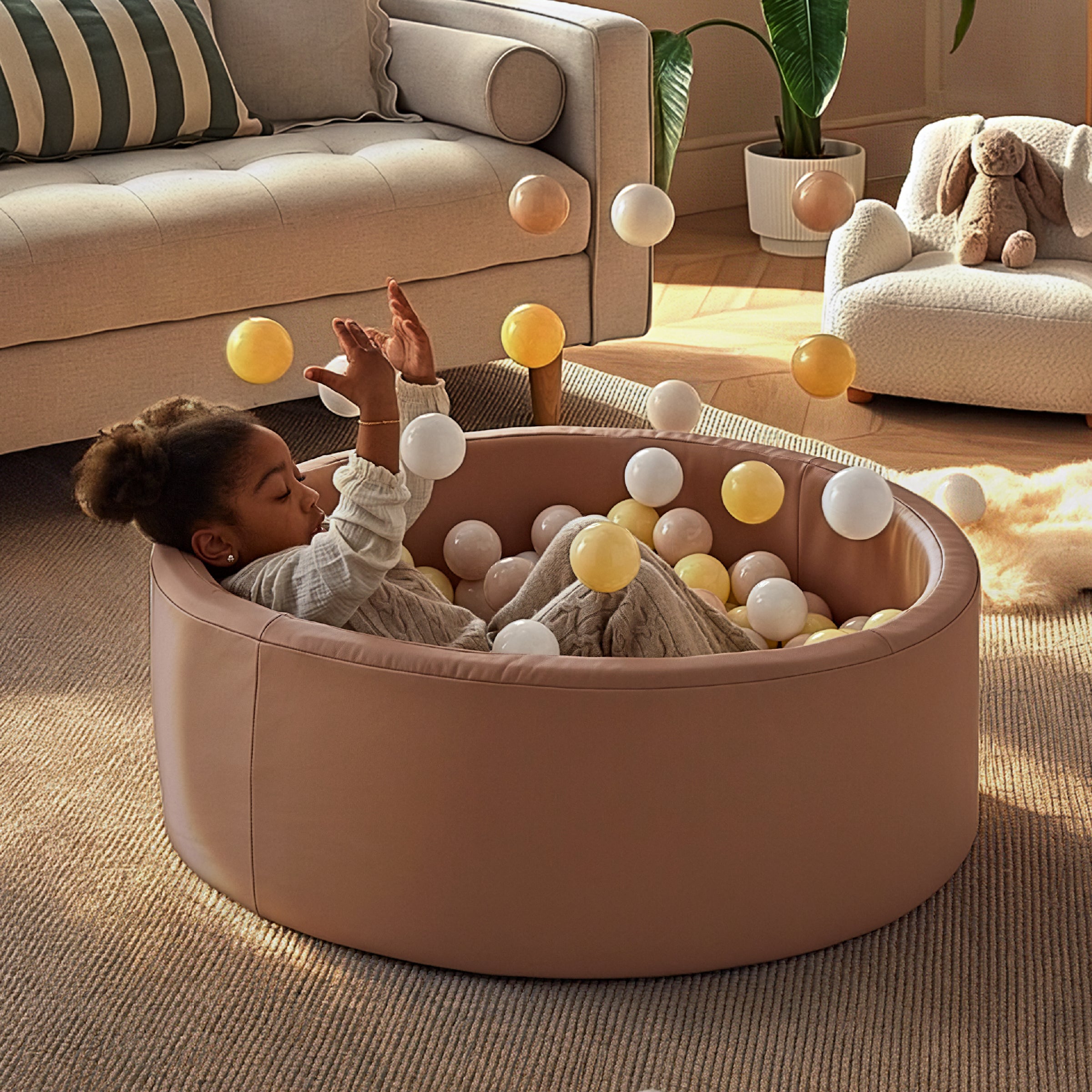 Child playing with balls in a ball pit in a living room.