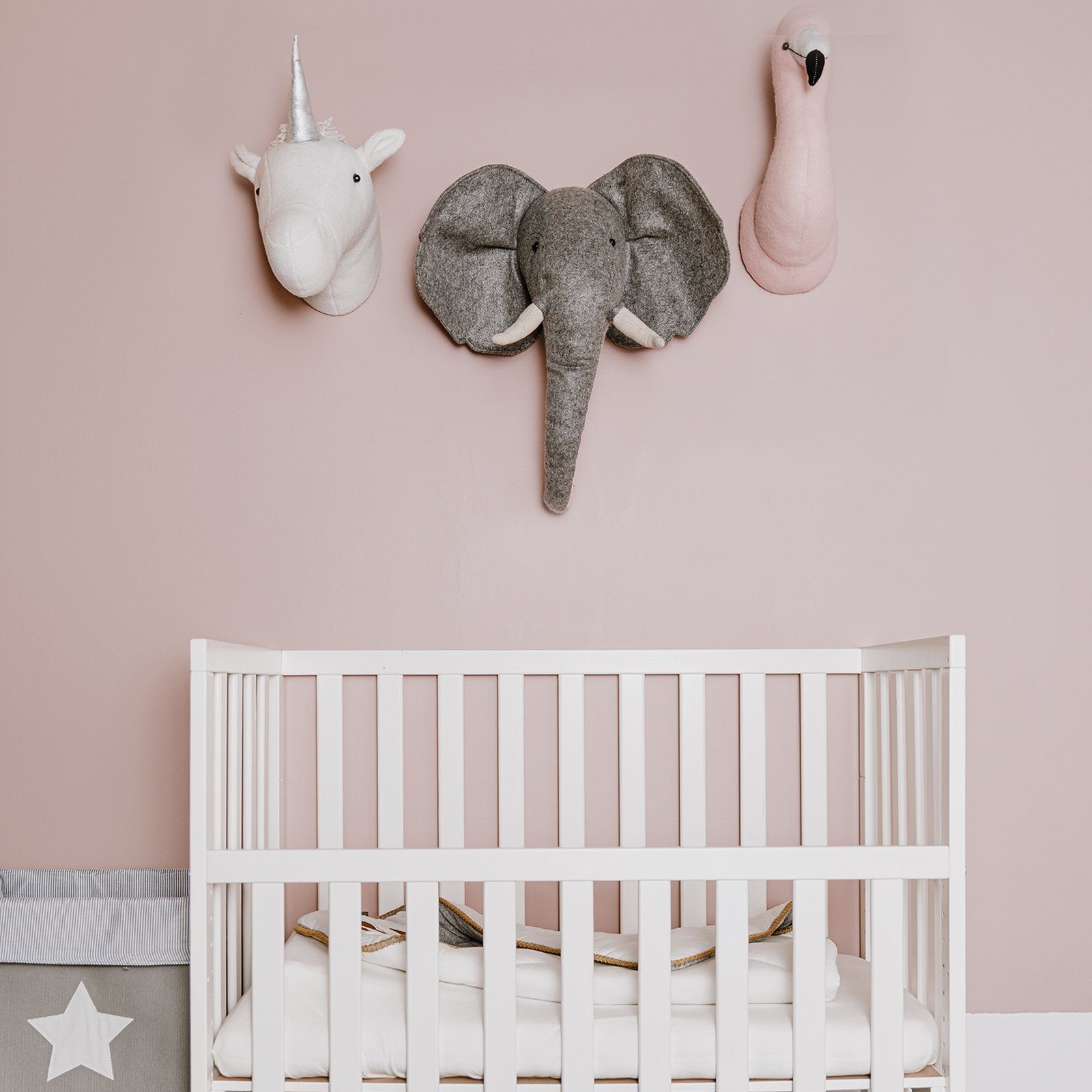 Elephant Head Wall Decor next to unicorn and flamingo head. Aboev a white cot in a nursery. Animal wall mounts by Childhome 